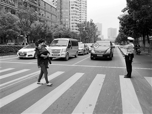 協(xié)警手持禮讓牌站在斑馬線前提醒來往車輛 記者 吳依瀅 攝